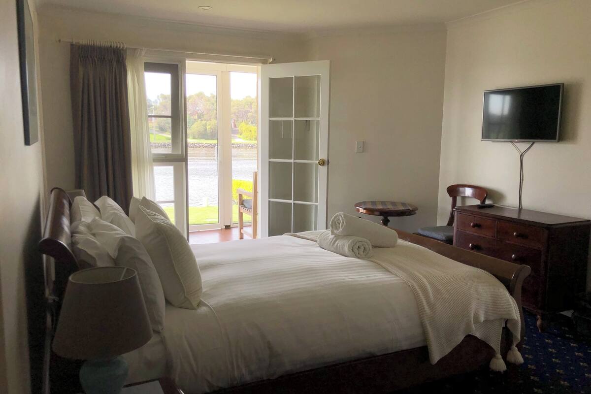 A hotel room with a bed, a desk, a chair, a television, and a view of the outdoors.