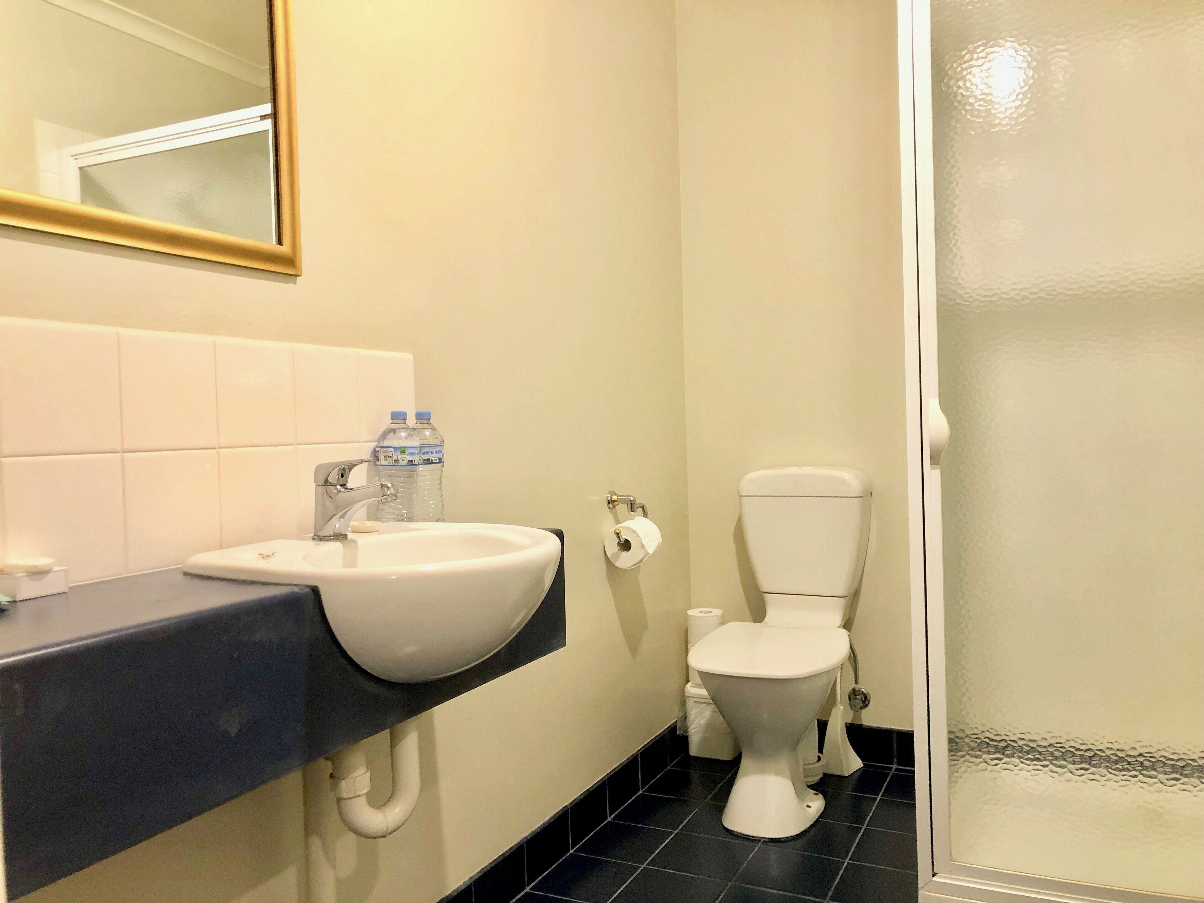 A bathroom with a sink, toilet, and a glass shower enclosure.