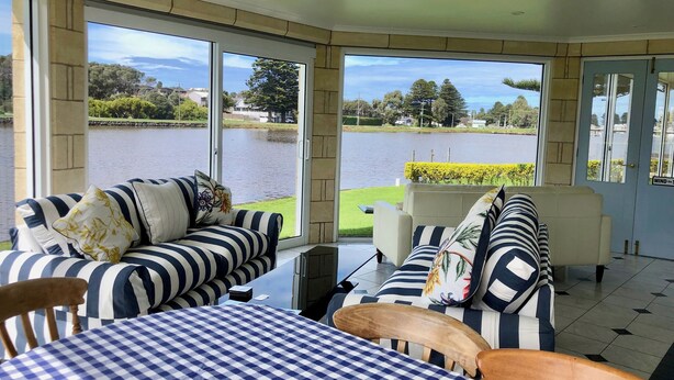 A room with a checkered table, striped sofas, and a view of a lake. - Douglas Riverside (Port Fairy)