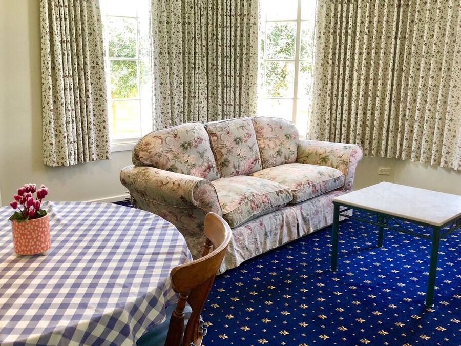 A living room with a floral sofa, a checkered table, and a blue patterned carpet.