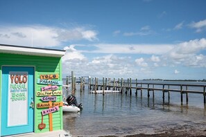 A green building with a sign listing activities like parasailing, sandbar, dolphin cruise, and kayak tours.
