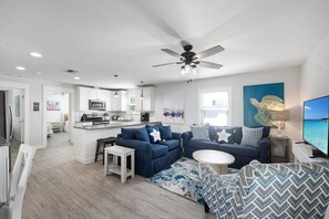 A modern living room with a blue sofa, a white coffee table, and a ceiling fan.