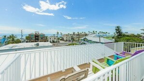 A balcony with a view of a beach and buildings. - Family Tides A – AMI Retreat w/ Pool, Rooftop Deck & Gulf/Bay Views Steps To Beach (Bradenton Beach)