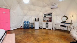 A spacious tent with a high ceiling, a central chandelier, a pink door, and a kitchenette area. - Southern Boho inspired Geodesic Dome nestled up next to Big Bend National Park. (Terlingua)