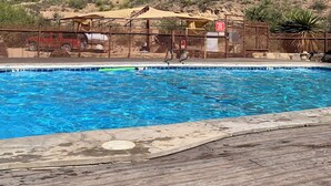 A swimming pool with a mountain backdrop, a fenced area with a jeep, and a shaded structure. - Southern Boho inspired Geodesic Dome nestled up next to Big Bend National Park. (Terlingua)