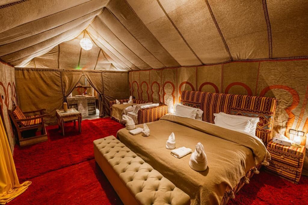 A tented room with a large bed, a small table, and a chair.