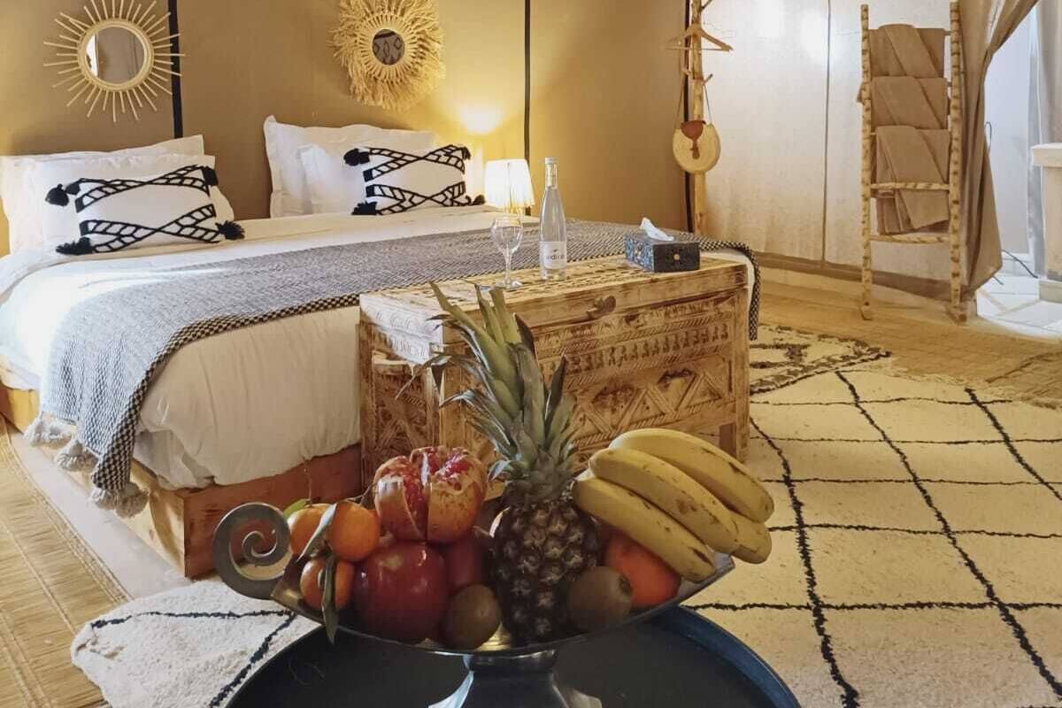 Una habitación con carpa, una cama, un frutero y luces colgantes.