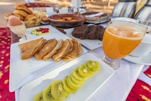 Una mesa con tostadas, rodajas de kiwi y un vaso de jugo de naranja.