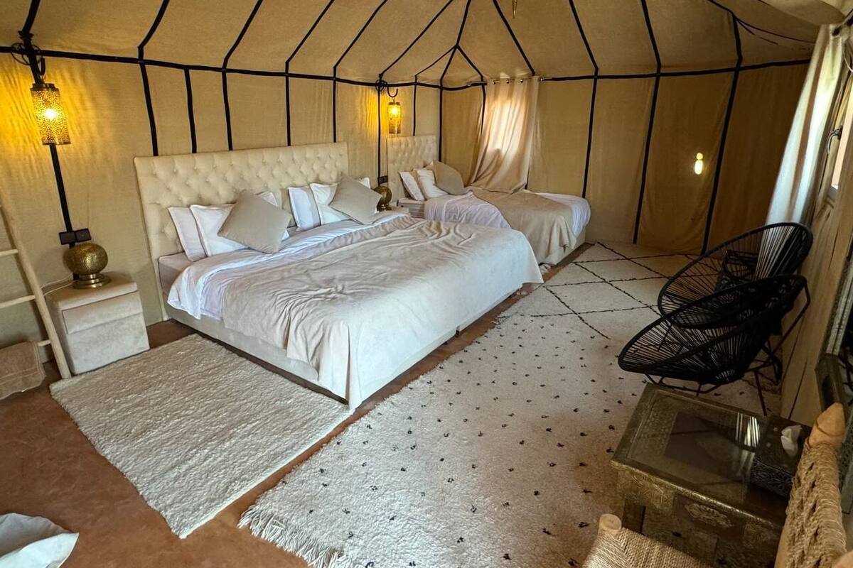 Habitación tipo alojamiento con dos camas, una mesita de noche, una silla y una pequeña mesa.