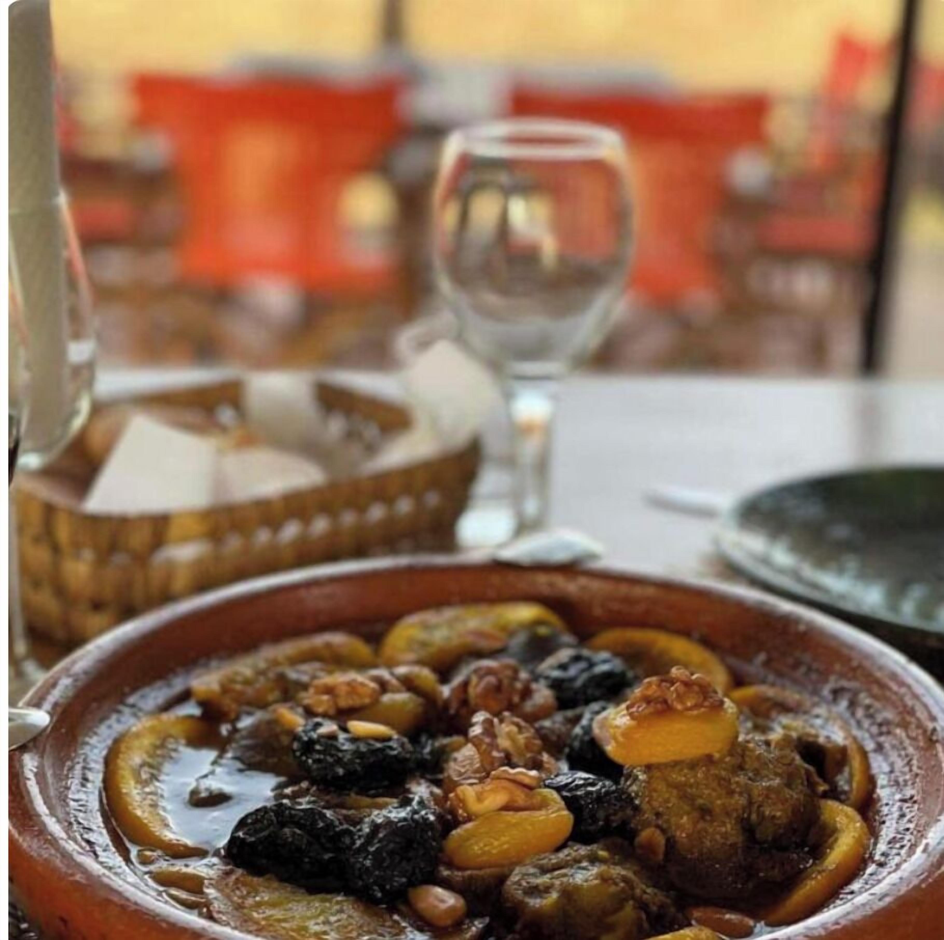 A dining table with a plate of food, a glass of water, and a basket of bread.