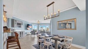 A spacious dining area with a large table and chairs, a kitchen with modern appliances, and a ceiling fan. - 3402 Windsor @ Palmetto Dunes | Oceanfront | Steps to Beach | Pool | Stunning Views (Hilton Head Island)