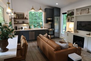 Une cuisine moderne avec des meubles de couleur sombre, un four encastré et une grande fenêtre donnant sur un espace verdoyant.