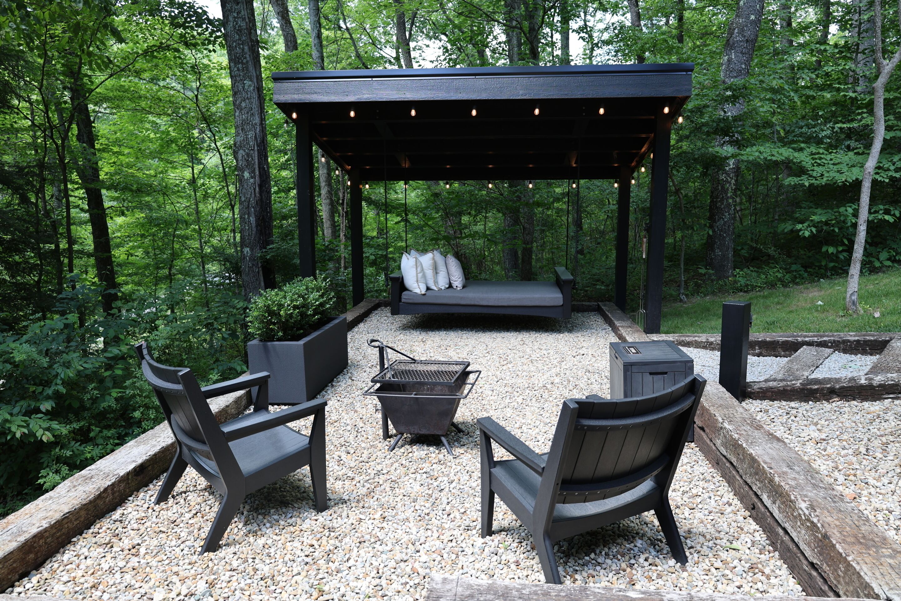 An outdoor seating area with a pergola, a grill, and a bench.