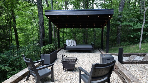 Un espace extérieur aménagé avec une pergola, un barbecue et un banc.