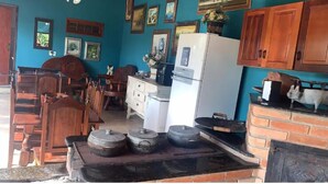 A kitchen with wooden cabinets, a refrigerator, and a brick stove. - Recanto das Orquideas (Quatis)