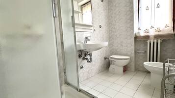 Un bagno con doccia, lavandino, WC e bidet.