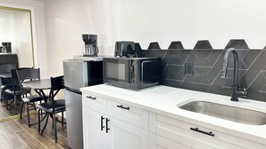 A modern kitchen with white cabinets, a black microwave, a coffee maker, and a black backsplash. - GETAWAY/PRIVATE SUITE C, (Lutz)