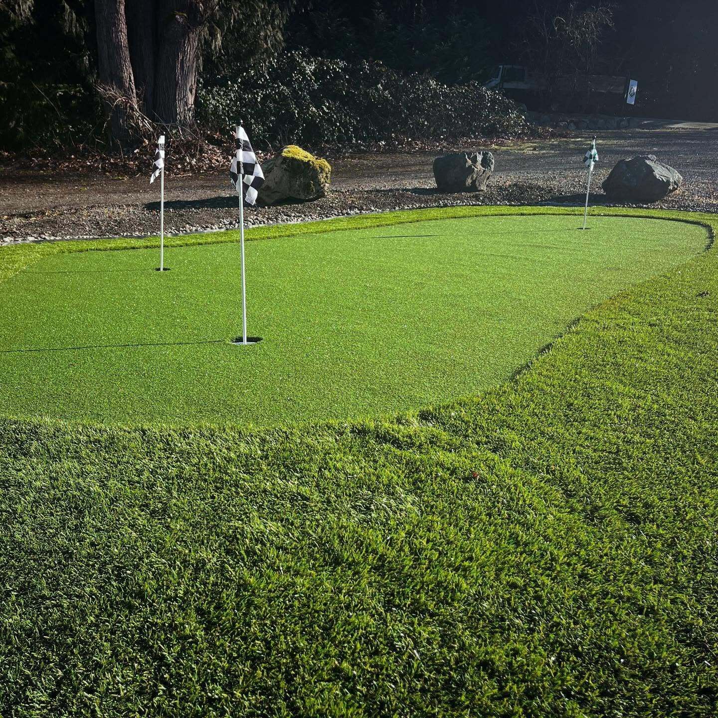 A well-maintained golf course with clear putting greens and a flagstick in the center.