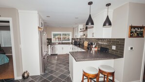 A modern kitchen with dark tiled flooring, white cabinetry, and a central island with stools. - Walk to Woodinville Wineries - Game Room - Fire Pit (Redmond)