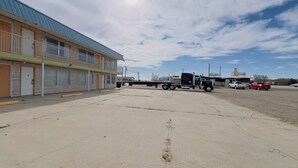 Een motel met een plat dak, meerdere kamers en een parkeerplaats.