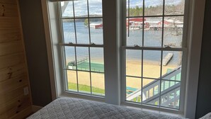 A room with a large window overlooking a beach and water. - Spectacular Sunset Suite (Laconia)