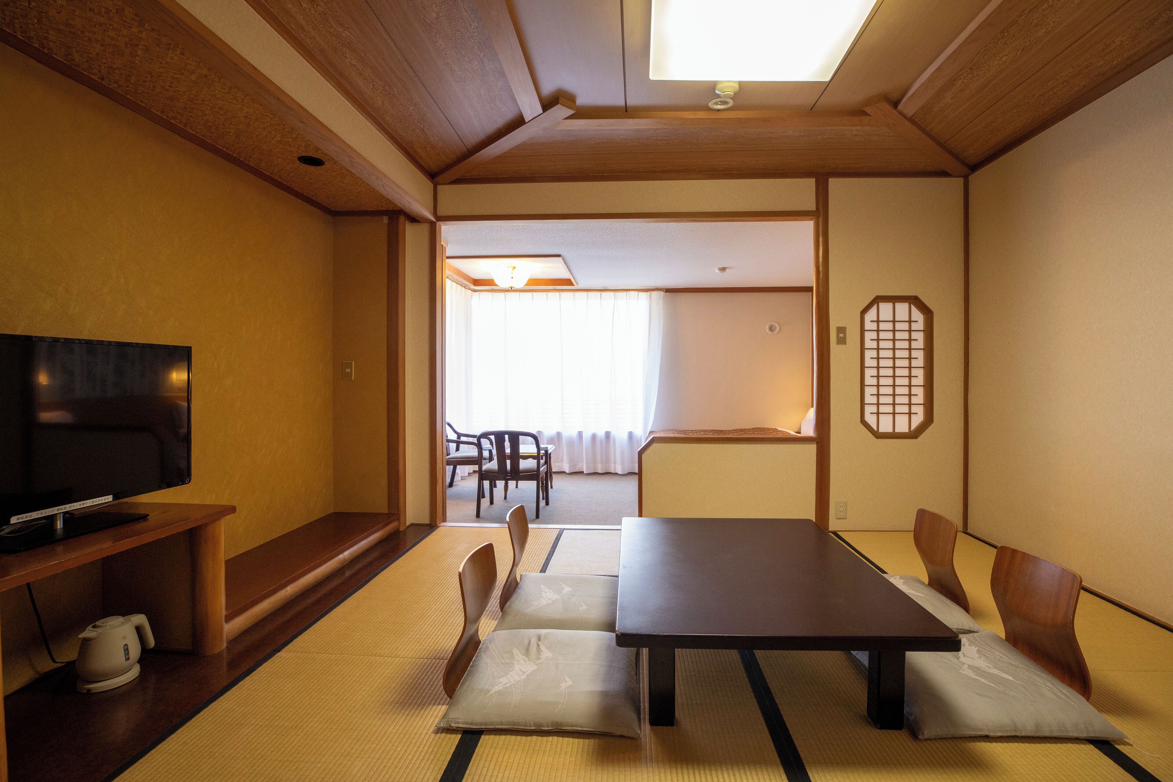 Ein traditioneller japanischer Raum mit Tatami-Matten, einem niedrigen Tisch und Holzstühlen.
