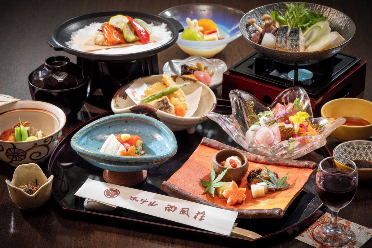 A variety of dishes and a glass of red wine on a table.