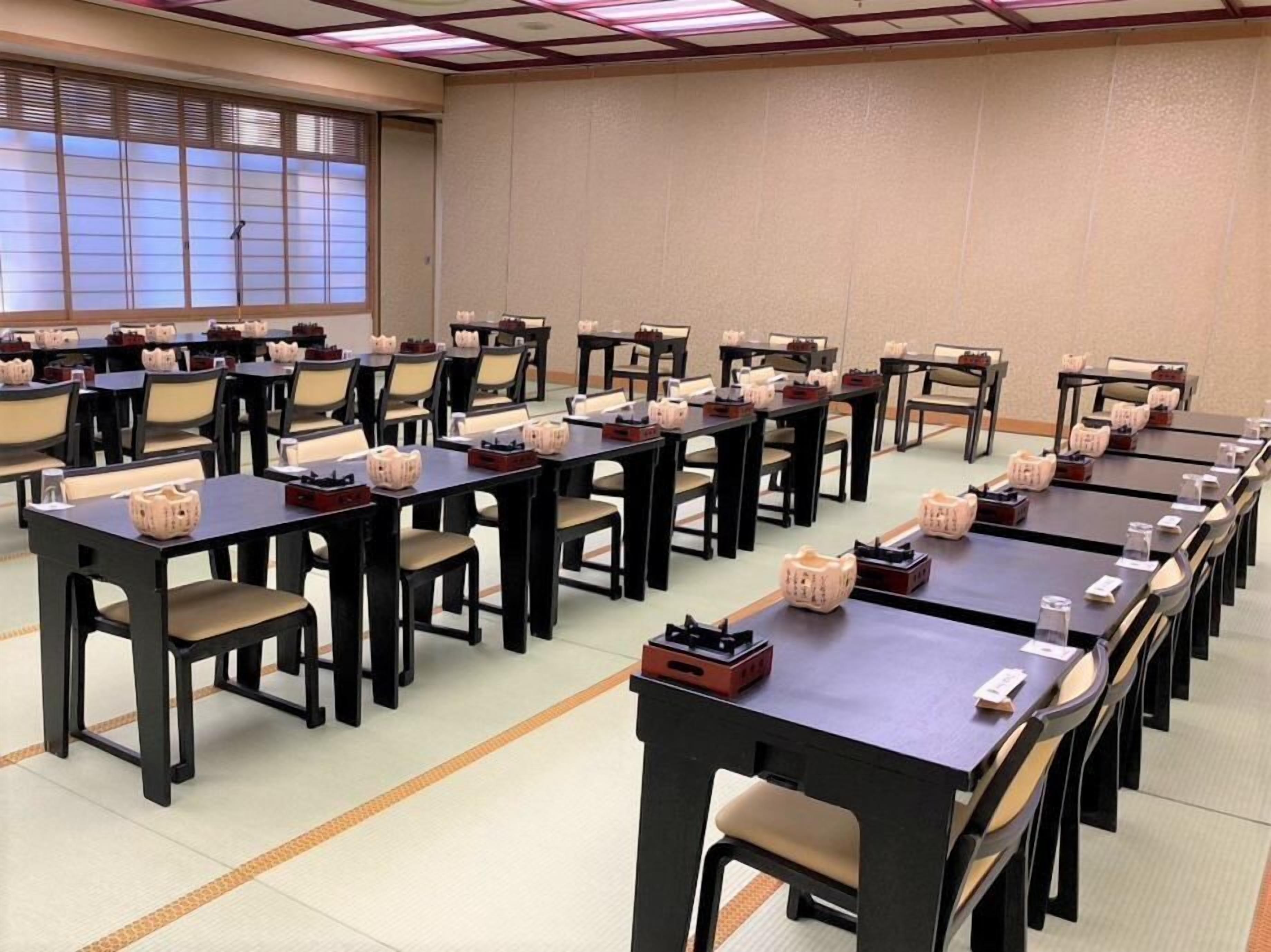 A conference room with multiple tables and chairs, arranged in rows.