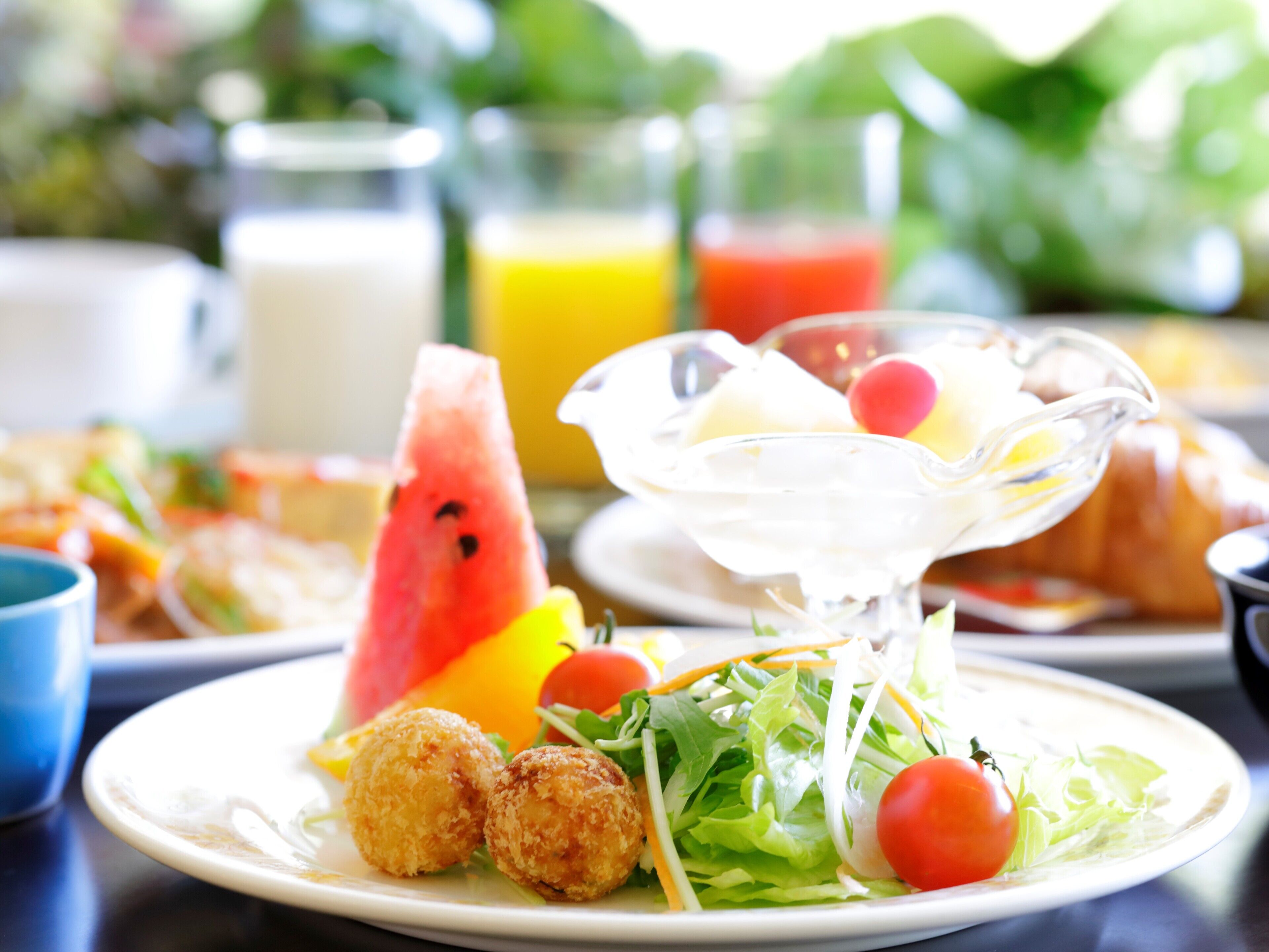 A breakfast setting with a plate of food, including croquettes, salad, and a glass of juice.