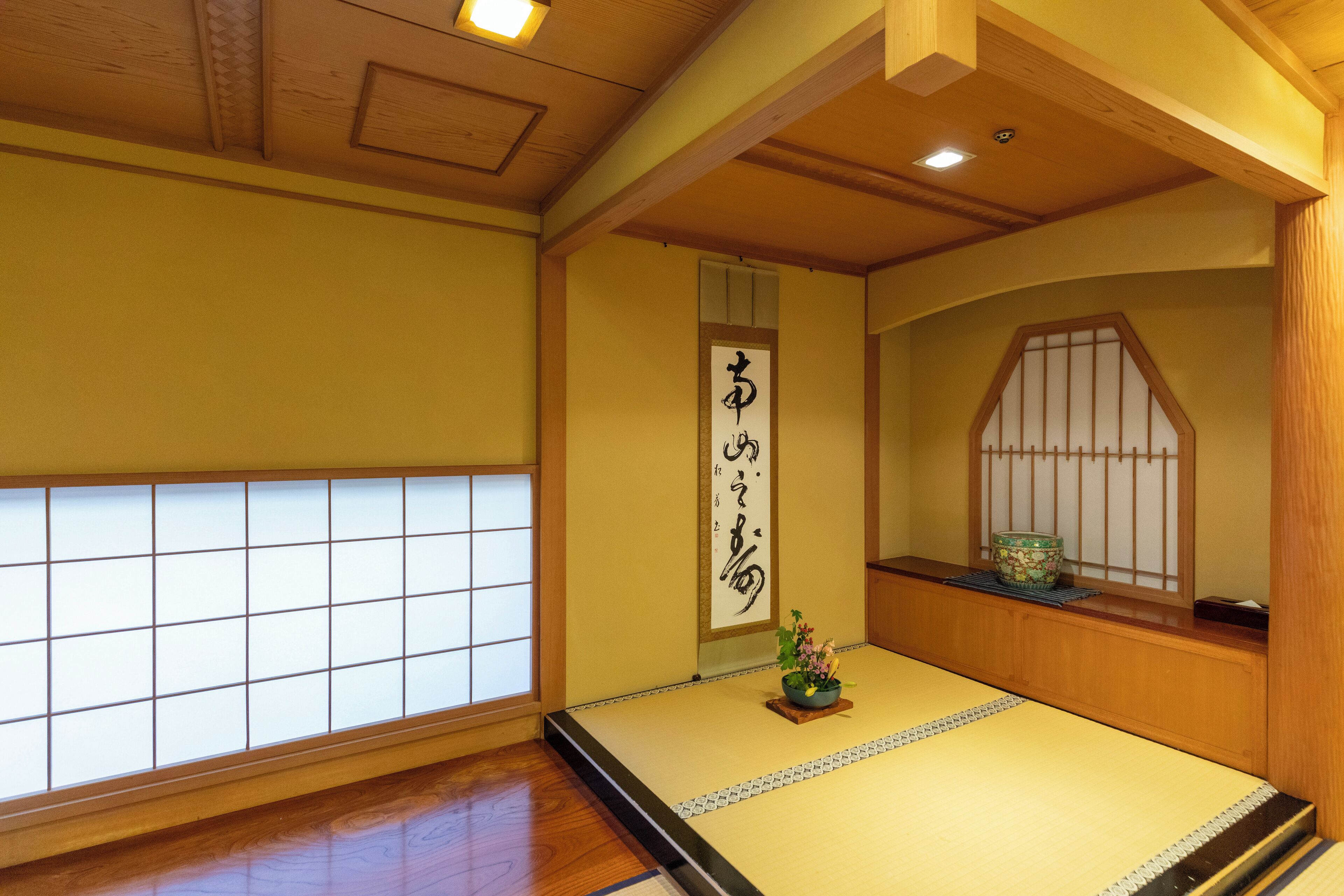 Una habitación tradicional japonesa con tatami, un biombio shoji y un pergamino de caligrafía.