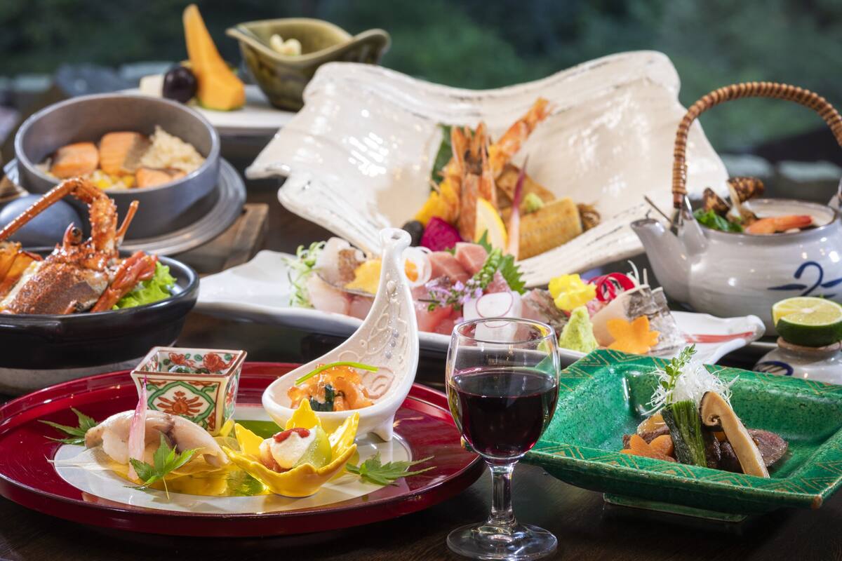 A variety of dishes on a table, including seafood, vegetables, and a glass of red wine.