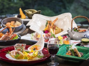 A variety of dishes on a table, including seafood, vegetables, and a glass of red wine.
