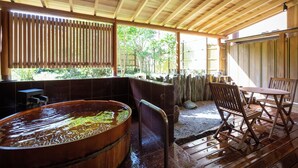 A wooden deck with a hot tub, seating area, and a view of greenery. - Hotel Nanpuso (Hakone)