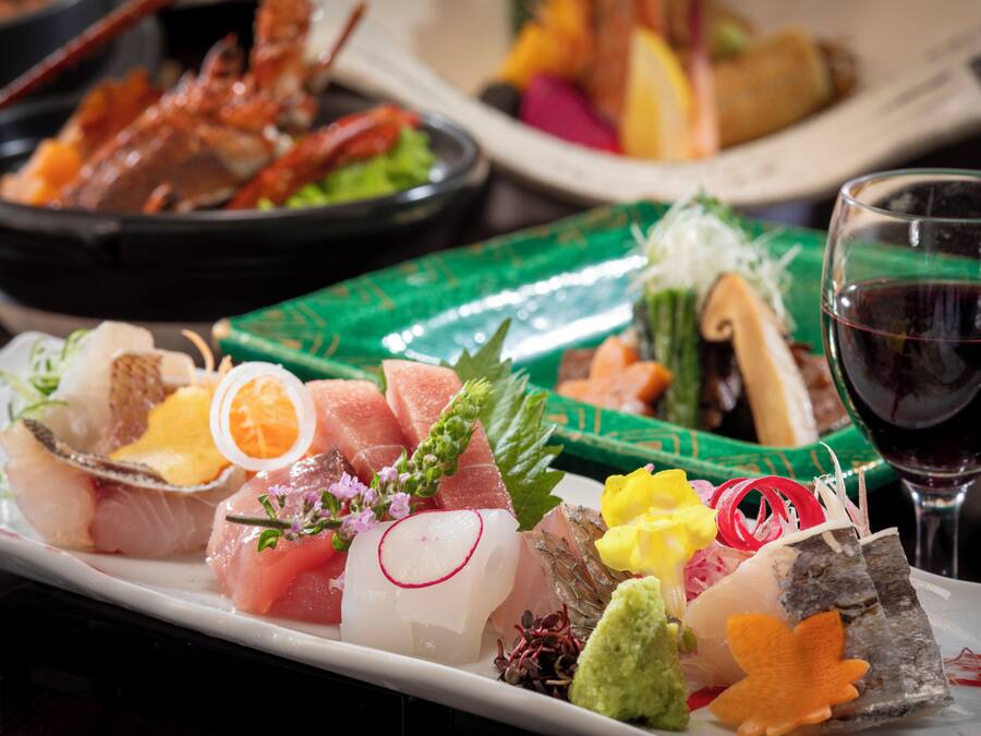 Assortimento di piatti di sushi accompagnati da un bicchiere di vino rosso.