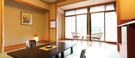Une salle de réunion de style japonais traditionnel, dotée d’un sol recouvert de tatamis, d’une table basse et offrant une vue sur l’extérieur grâce à de grandes fenêtres.