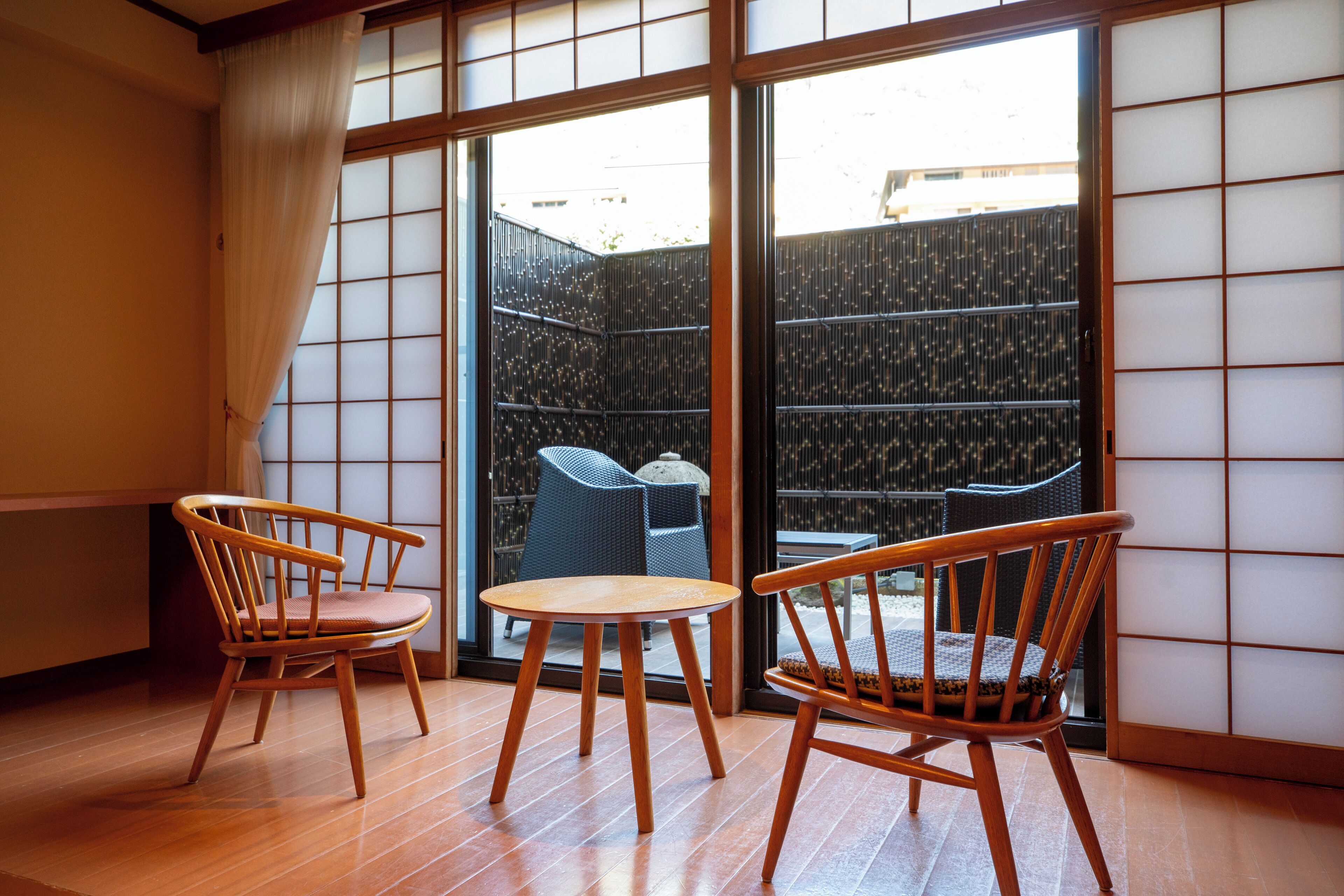 Um quarto japonês tradicional com piso de tatame, uma porta de tela deslizante shoji e duas cadeiras de madeira com almofadas.