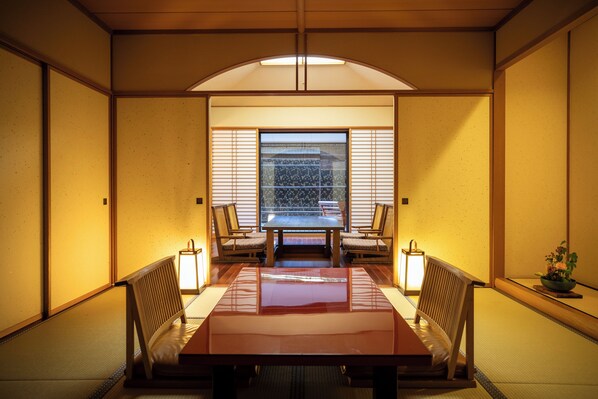 Una habitación japonesa tradicional con suelo de tatami, una mesa baja y puertas correderas shoji.