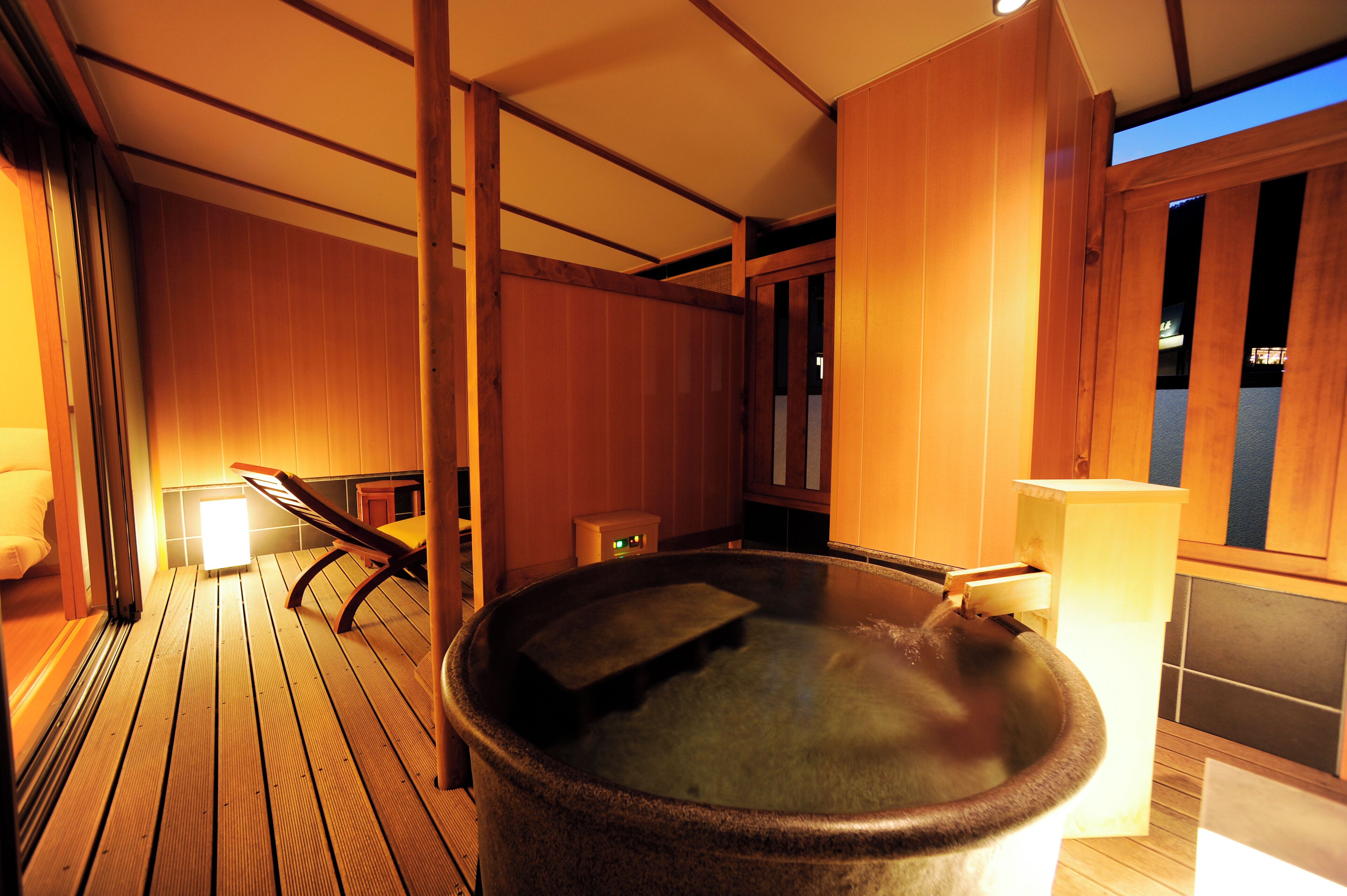 A wooden deck with a hot tub, wooden walls, and a bench.