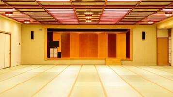Een kamer met tatami vloerbedekking, een traditionele Japanse schuifdeur en een televisie op een standaard.