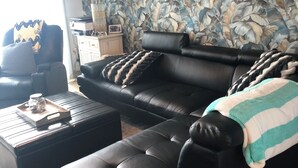 Una sala de estar con un sofá de cuero negro, una mesa de centro con una bandeja y un papel tapiz estampado.
