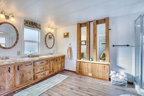 Une salle de bain spacieuse avec des meubles en bois, un grand miroir et une cabine de douche en verre.
