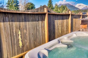 Une terrasse en bois avec un jacuzzi et une vue sur les montagnes en arrière-plan.