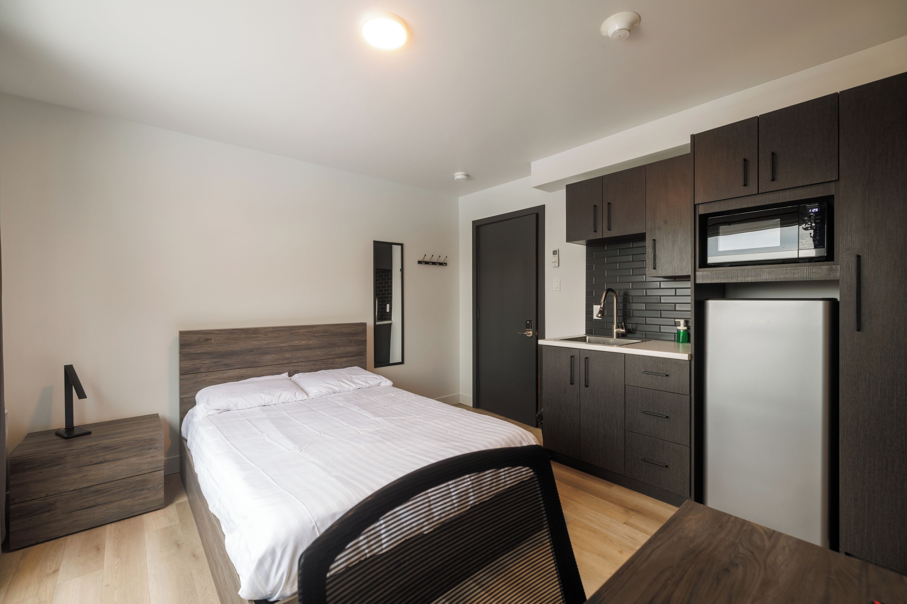 A modern bedroom with a bed, bedside table, and a small desk with a chair.