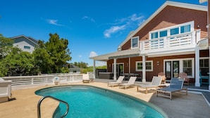 A house with a swimming pool, a covered patio, and a two-story balcony. - OBX Rays: Stunning Soundfront Home, Private Heated Pool, Hot Tub, Community Amenities (Corolla)