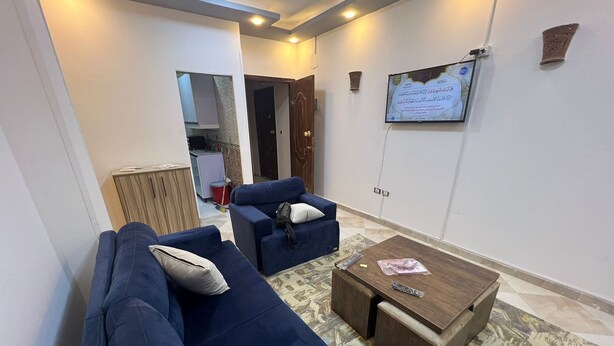 A living room with a blue sofa, a wooden coffee table, and a patterned rug. - Spacious 2-Bedroom Apartment (Hurghada)
