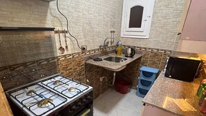 A compact kitchen with a gas stove, oven, and a small sink. - Spacious 2-Bedroom Apartment (Hurghada)