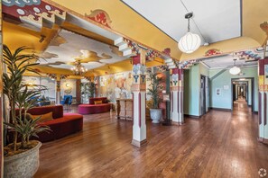 A spacious lobby with wooden flooring, red sofas, and decorative pillars. -  The Nirvana Apartment Hotel (Los Angeles)