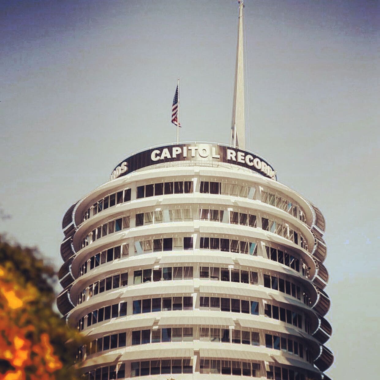 A multi-story building with a curved facade and a flag on top.