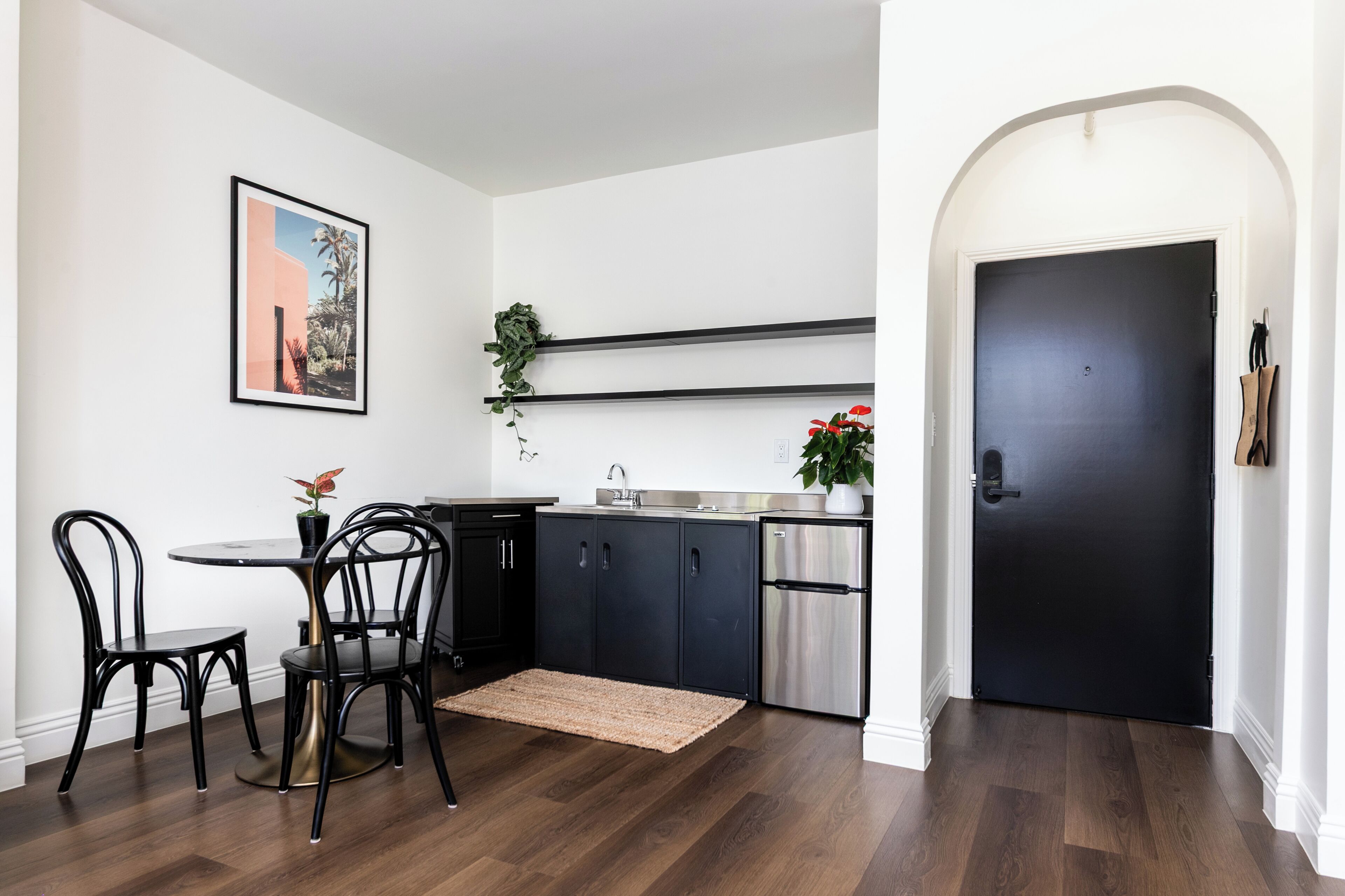 Una cuina moderna amb armaris foscos, un refrigerador d'acer inoxidable i una porta negra.