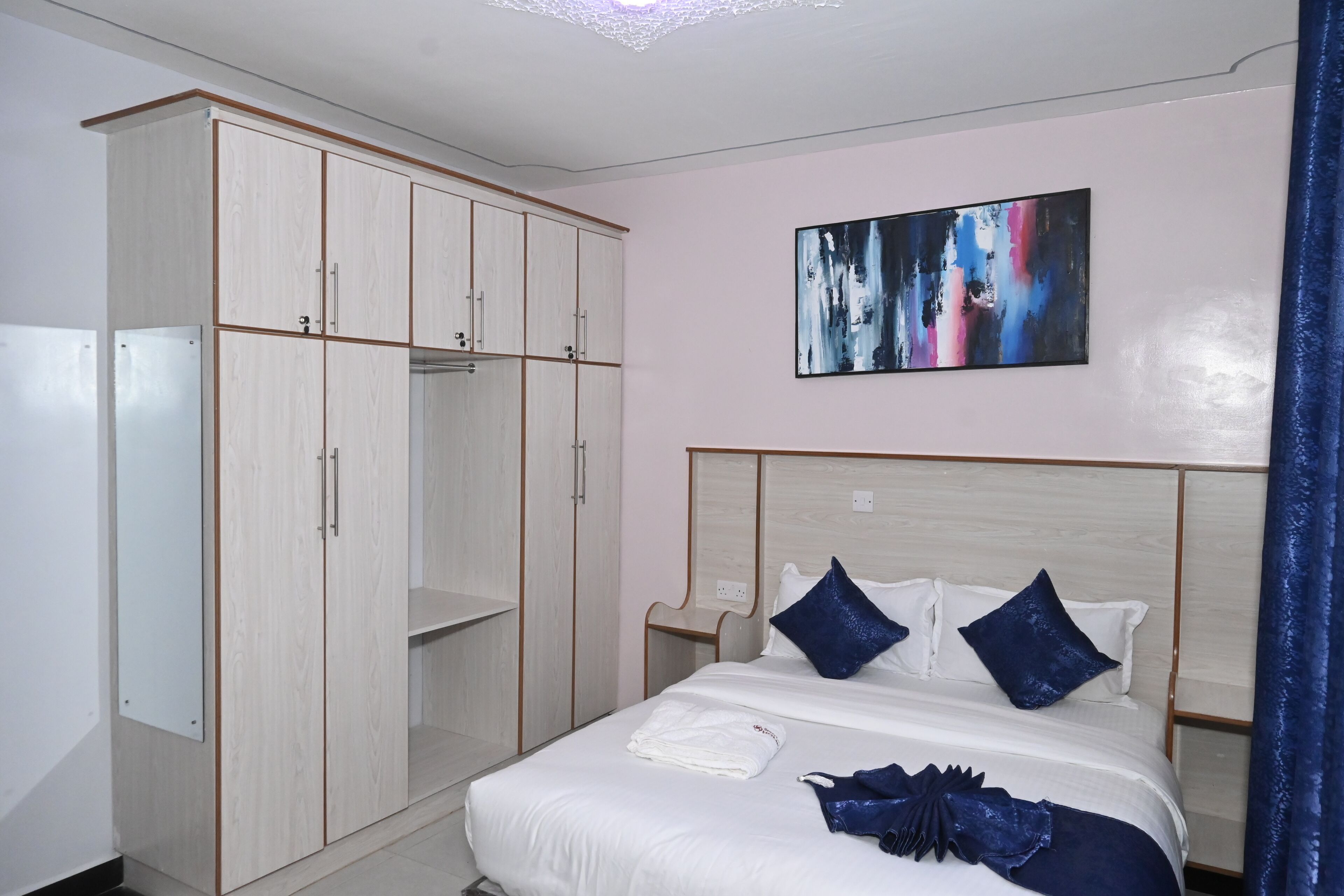 Un dormitorio con cama, armario y un cuadro en la pared.